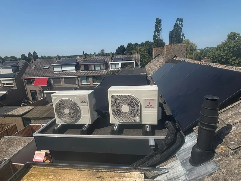 Twee airco-buitenunits op een plat dak naast zonnepanelen