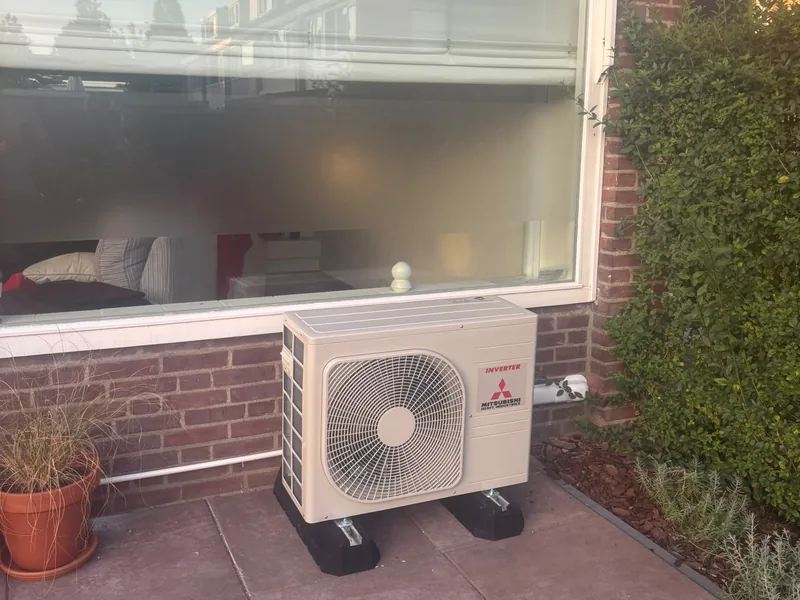 Airco-buitenunit op een terras voor een groot raam