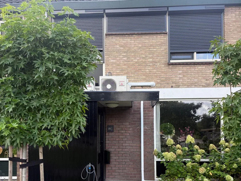 Rijtjeswoning met een airco-buitenunit boven de voordeur