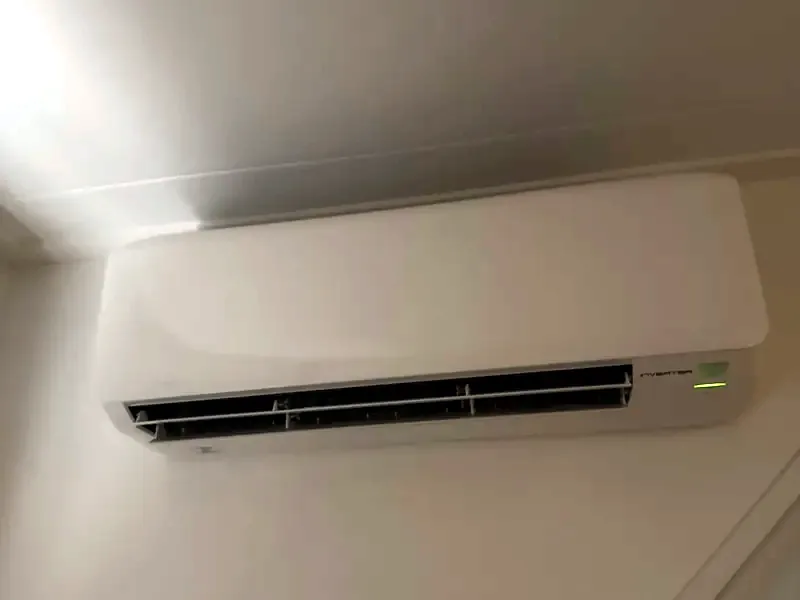 Witte airco-binnenunit hoog aan de wand