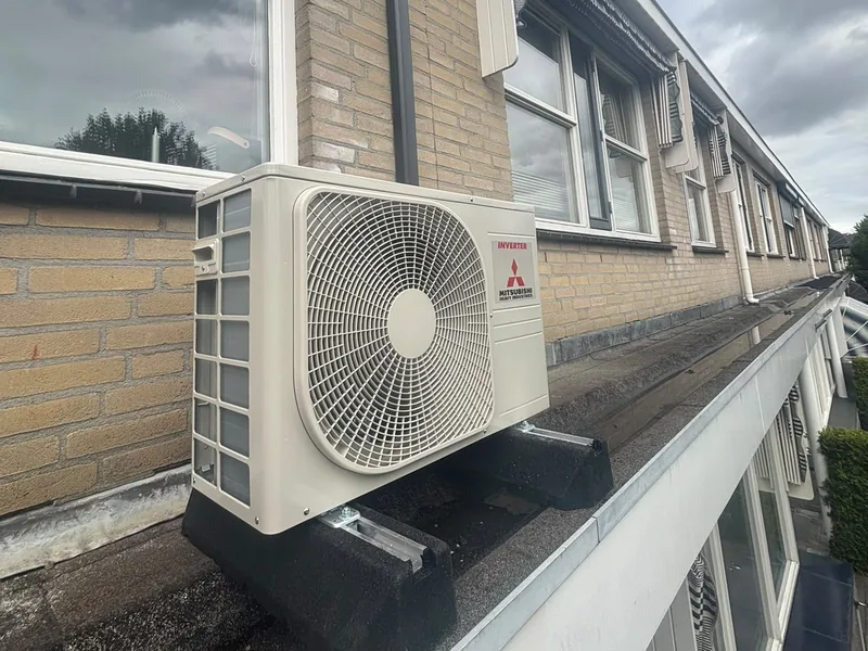 Airco-buitenunit op de dakrand van een rij woningen
