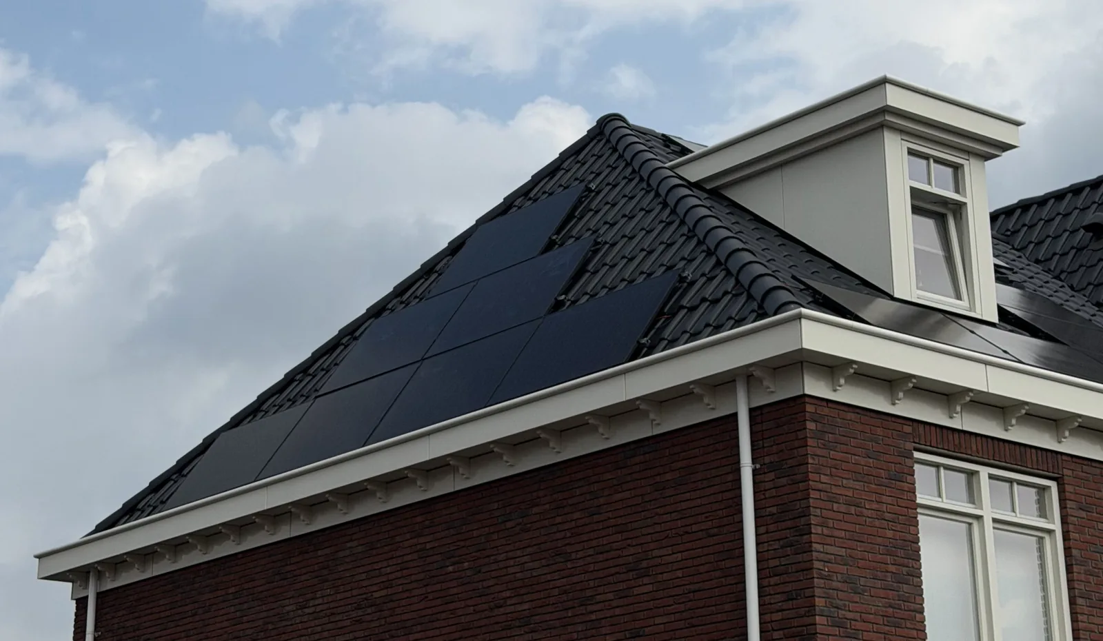 Woning met een donker pannendak, zwarte zonnepanelen en een dakkapel