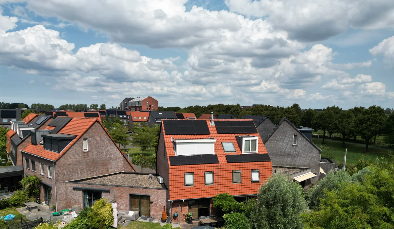 Woning met een oranje pannendak en zonnepanelen, van bovenaf, met veel lucht