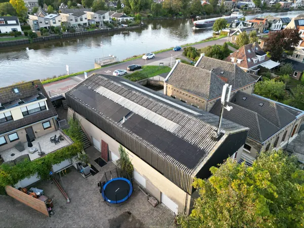 Loods aan het water met zonnepanelen op het golfplatendak, van bovenaf