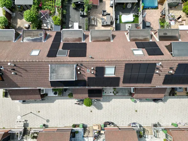 Rij woningen van bovenaf met zonnepanelen tussen de dakkapellen