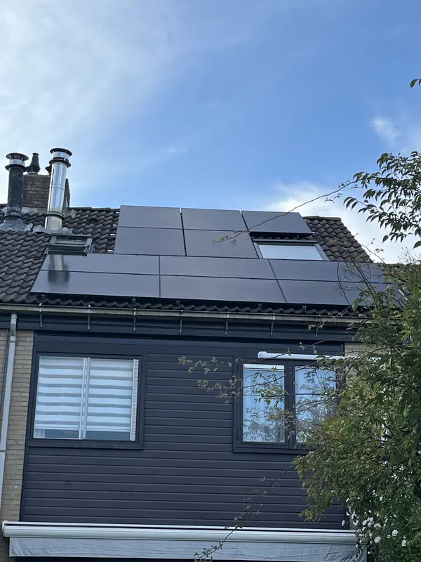 Zwarte zonnepanelen op het dak boven een houten gevel