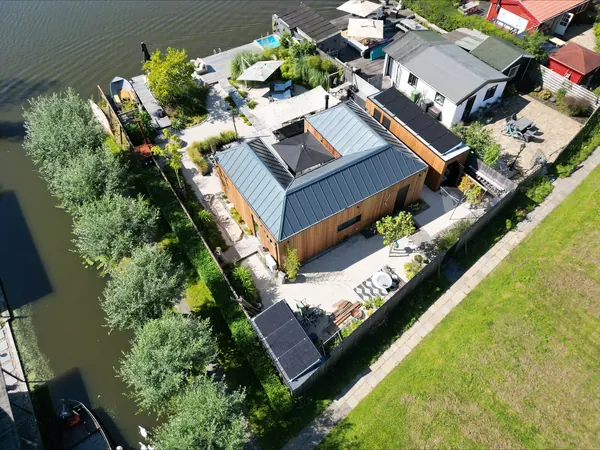 Woning aan het water met zonnepanelen op het dak van de schuur, van bovenaf