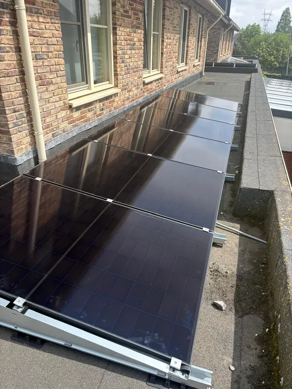 Rij zonnepanelen op het platte dak van een bakstenen appartementengebouw