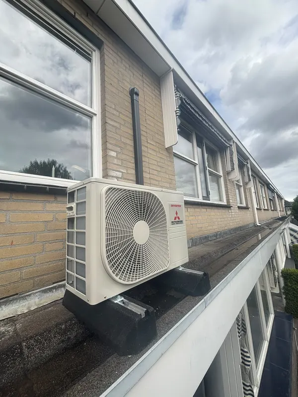 Airco-buitenunit op de dakrand van een rij woningen