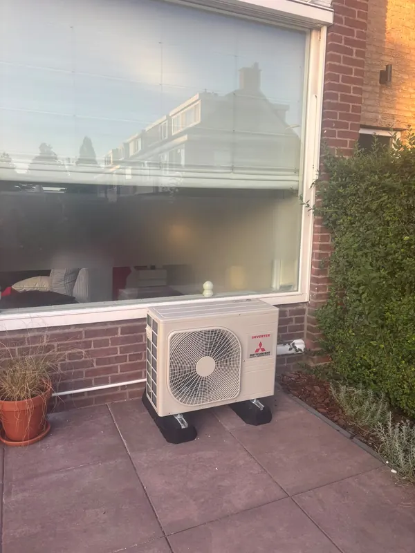 Airco-buitenunit op een terras voor een groot raam
