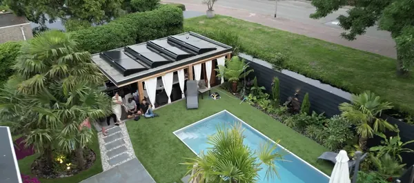 Tuinhuis met zonnepanelen op het dak, naast een zwembad