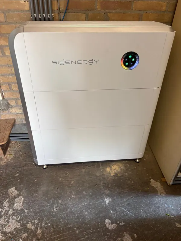 Sigenergy-thuisbatterij in een berging met een stenen muur