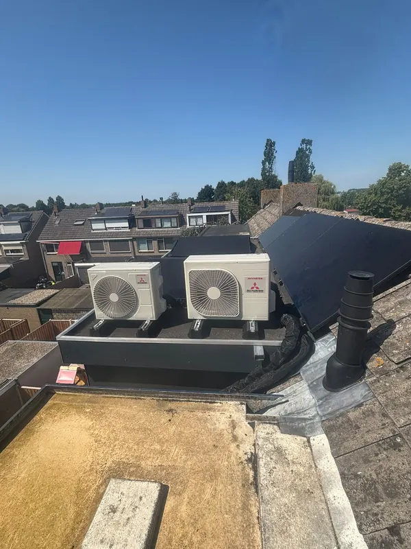 Twee airco-buitenunits op een plat dak naast zonnepanelen
