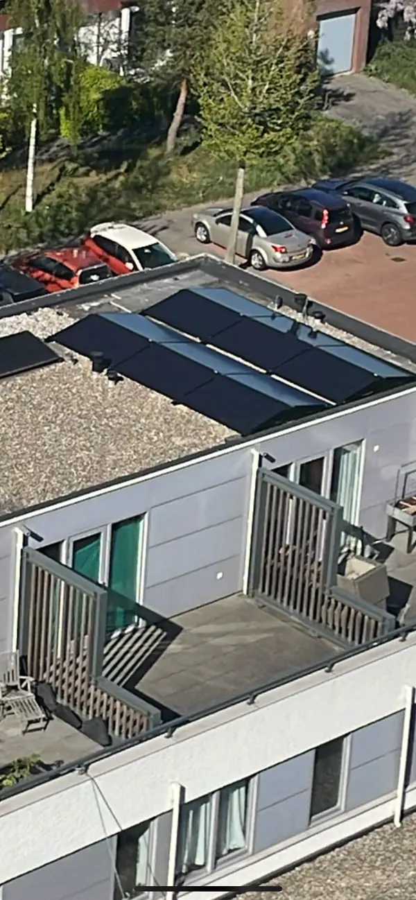 Zonnepanelen op het dak van een appartementengebouw met balkons, van bovenaf