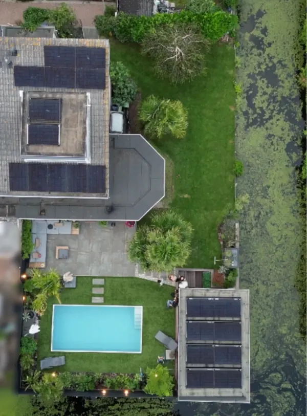 Woning en tuin van bovenaf met zonnepanelen op het platte dak en op de schuur