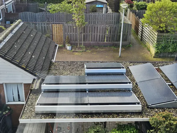 Zonnepanelen op frames op het grinddak van een aanbouw