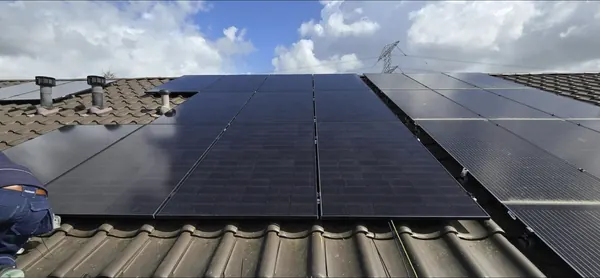 Rij zwarte zonnepanelen op een pannendak, van dichtbij