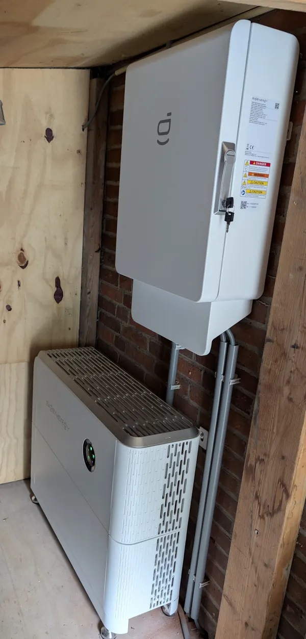 Hybride omvormer met een thuisbatterij eronder in een houten kast