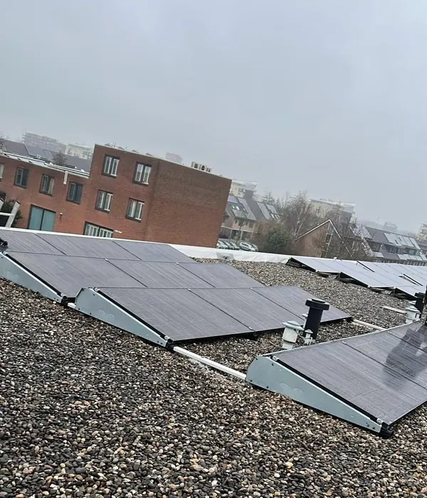 Zonnepanelen op een grinddak tussen appartementengebouwen