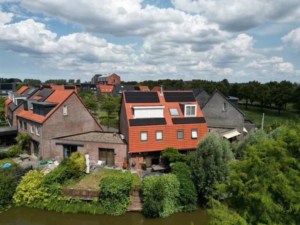 Twee woningen aan het water met zonnepanelen op de oranje pannendaken