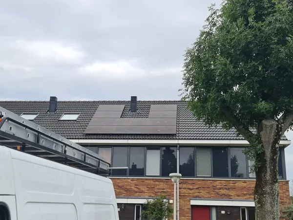 Rijtjeswoning met zonnepanelen, met een bus met ladders ervoor