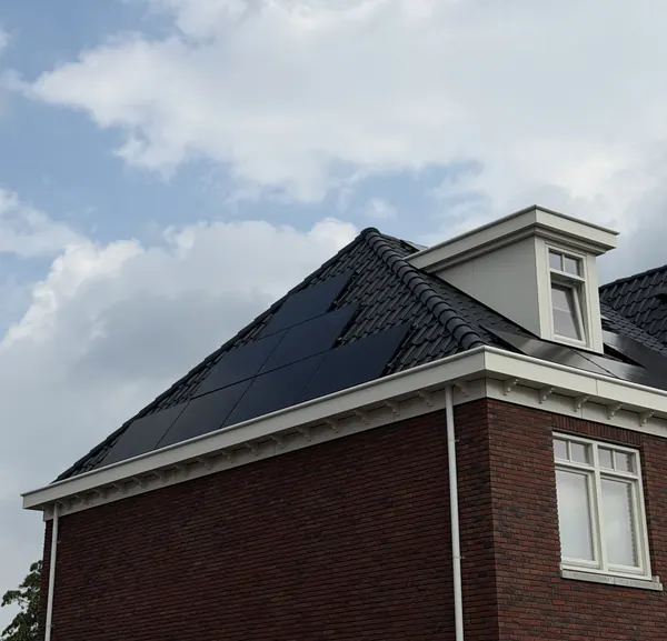 Zonnepanelen naast een dakkapel op een zwart pannendak