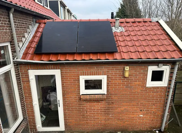 Zonnepanelen op het oranje pannendak van een aanbouw