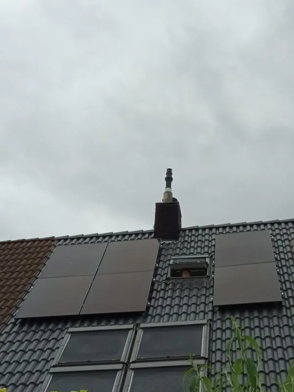 Zonnepanelen rond een dakraam op een zwart pannendak