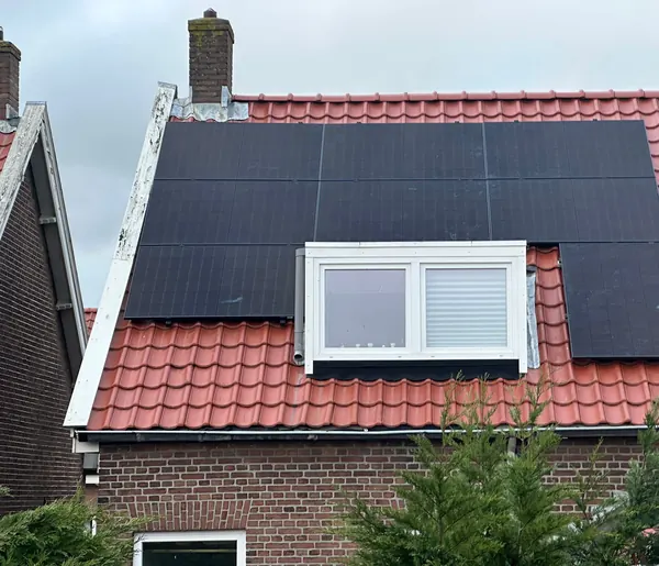 Zonnepanelen rond een dakkapel op een rood pannendak