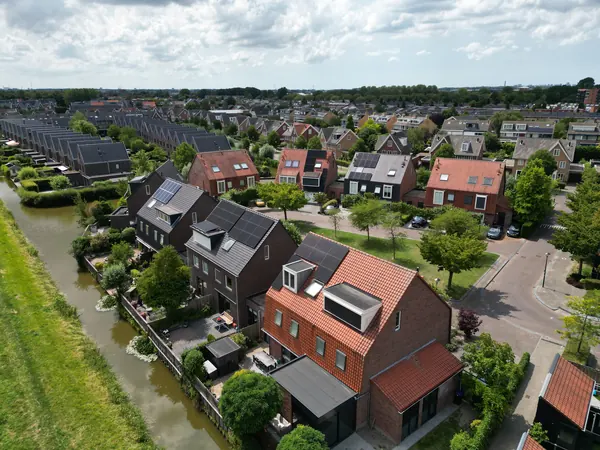 Woonwijk aan het water met zonnepanelen op meerdere daken