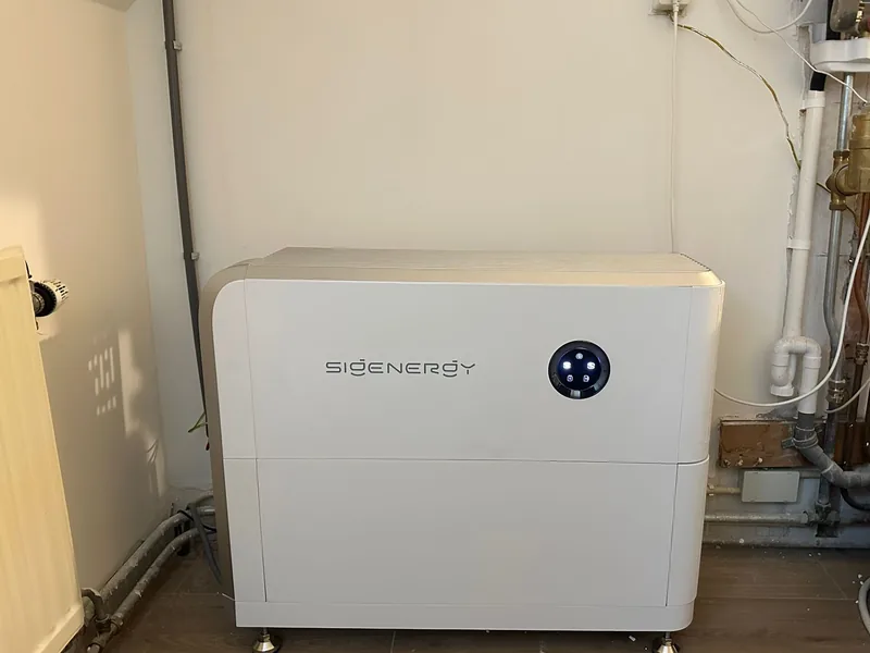 Sigenergy-thuisbatterij in een bijkeuken, naast leidingen en een radiator