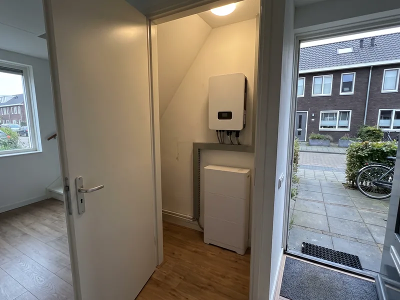 Omvormer aan de wand met een thuisbatterij eronder in een trapkast