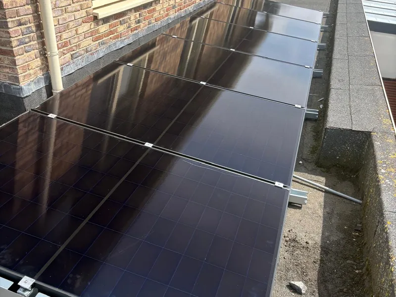 Rij zonnepanelen op het platte dak van een bakstenen appartementengebouw