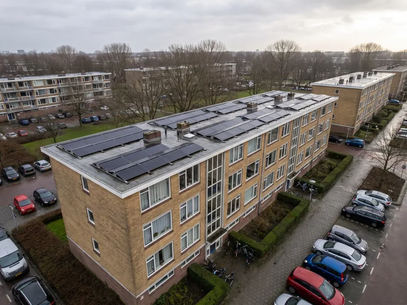 Portiekflat van bovenaf met rijen zonnepanelen op het platte dak