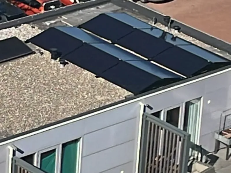 Zonnepanelen op het dak van een appartementengebouw met balkons, van bovenaf