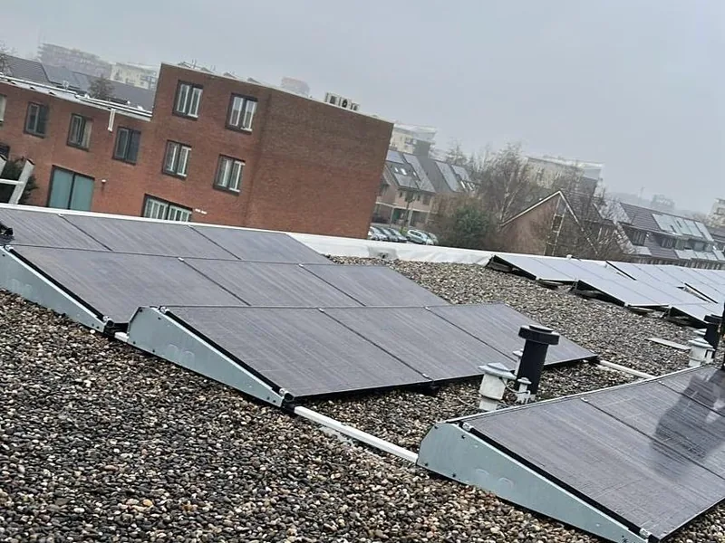 Zonnepanelen op een grinddak tussen appartementengebouwen
