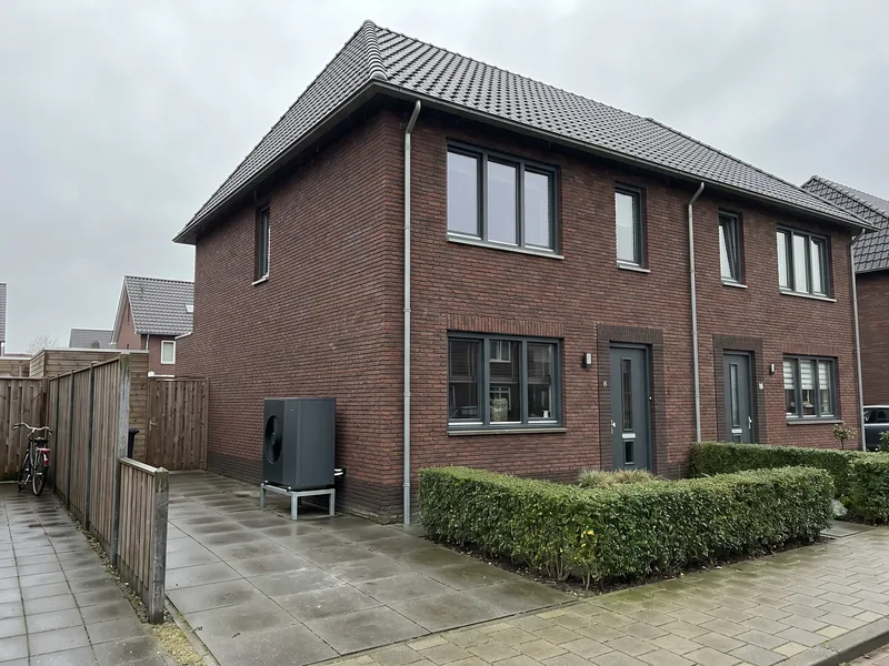 Nieuwbouwwoning met een warmtepomp-buitenunit naast het huis