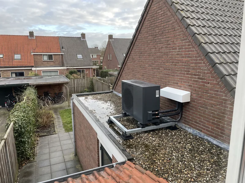 Warmtepomp-buitenunit op het platte dak van een aanbouw