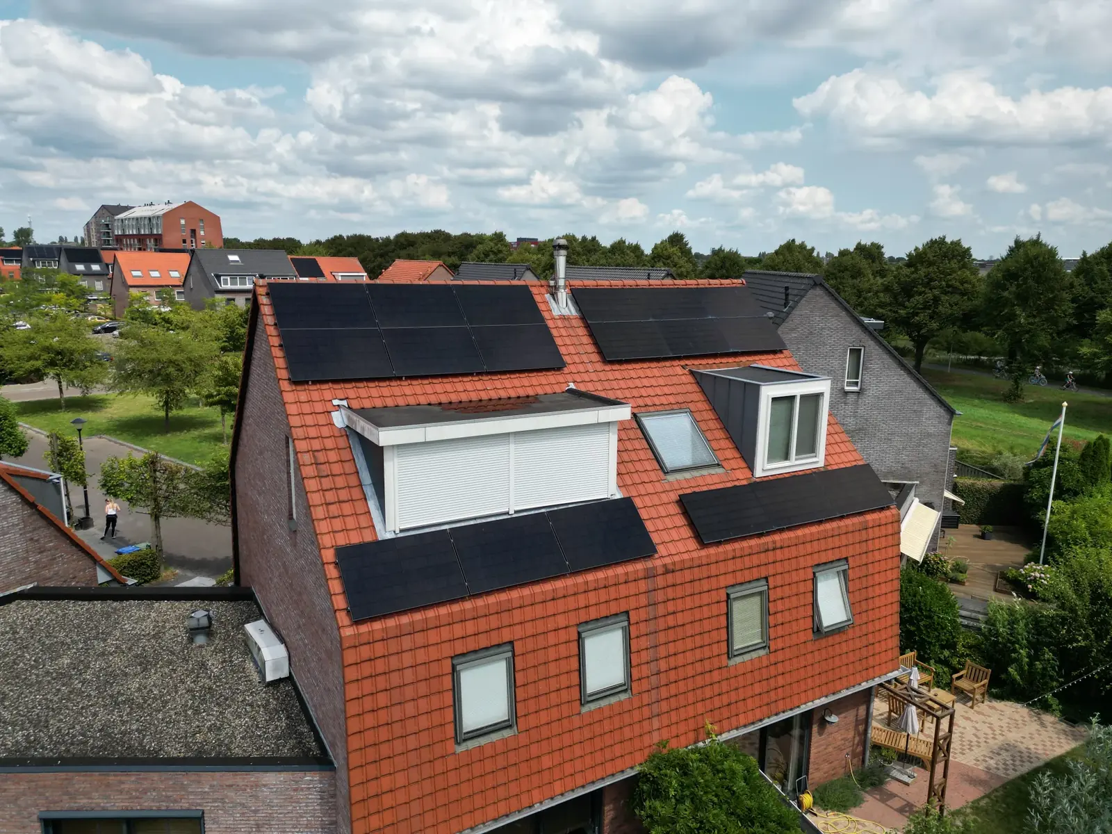 Woning met een oranje pannendak en zwarte zonnepanelen, van bovenaf gezien