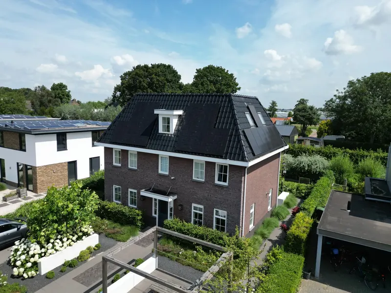 Vrijstaande woning met zwarte zonnepanelen op een donker schilddak