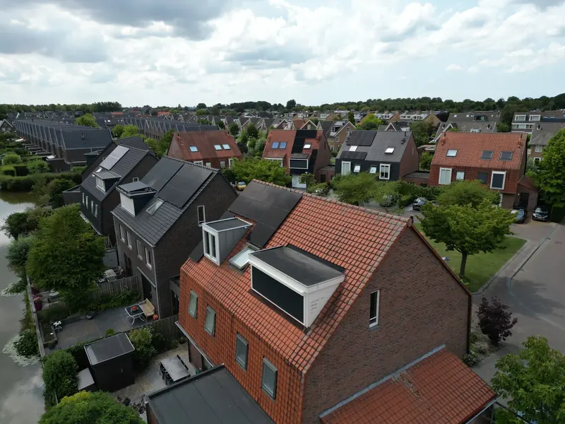 Woning met oranje dakpannen en zwarte zonnepanelen aan het water